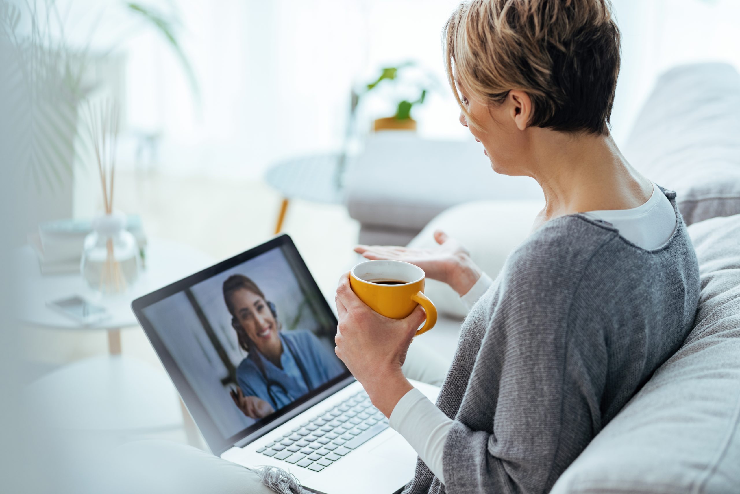 Woman using laptop and having video call with her doctor while s